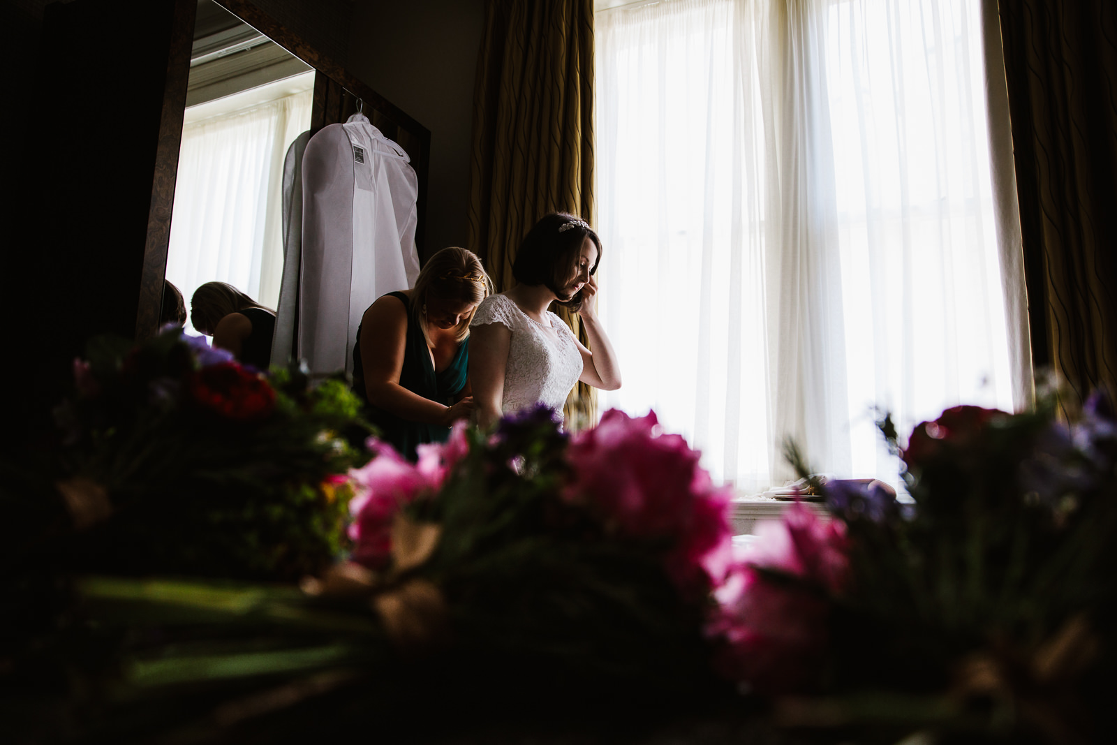 Bridesmaid helping bride into her dress at the Midland Hotel.