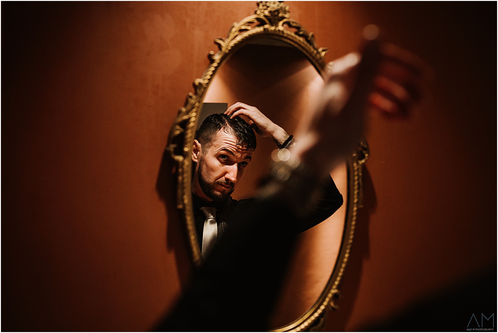 Groom doing his hair in the mirror