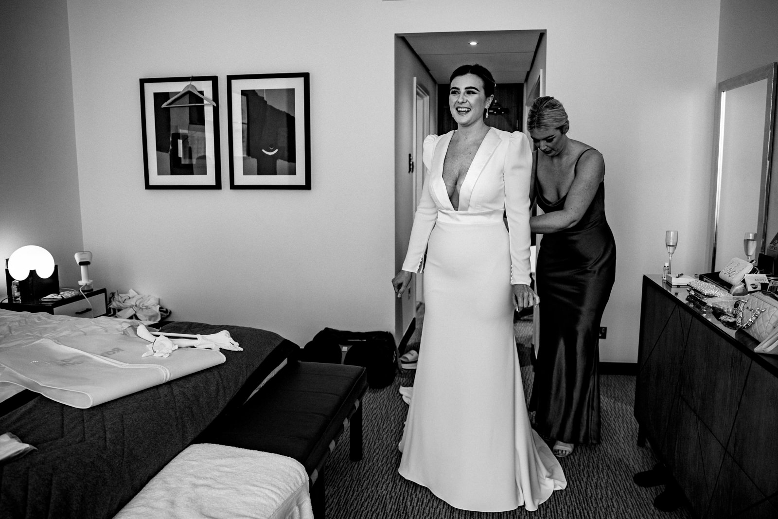 Bridesmaid helping bride into her dress