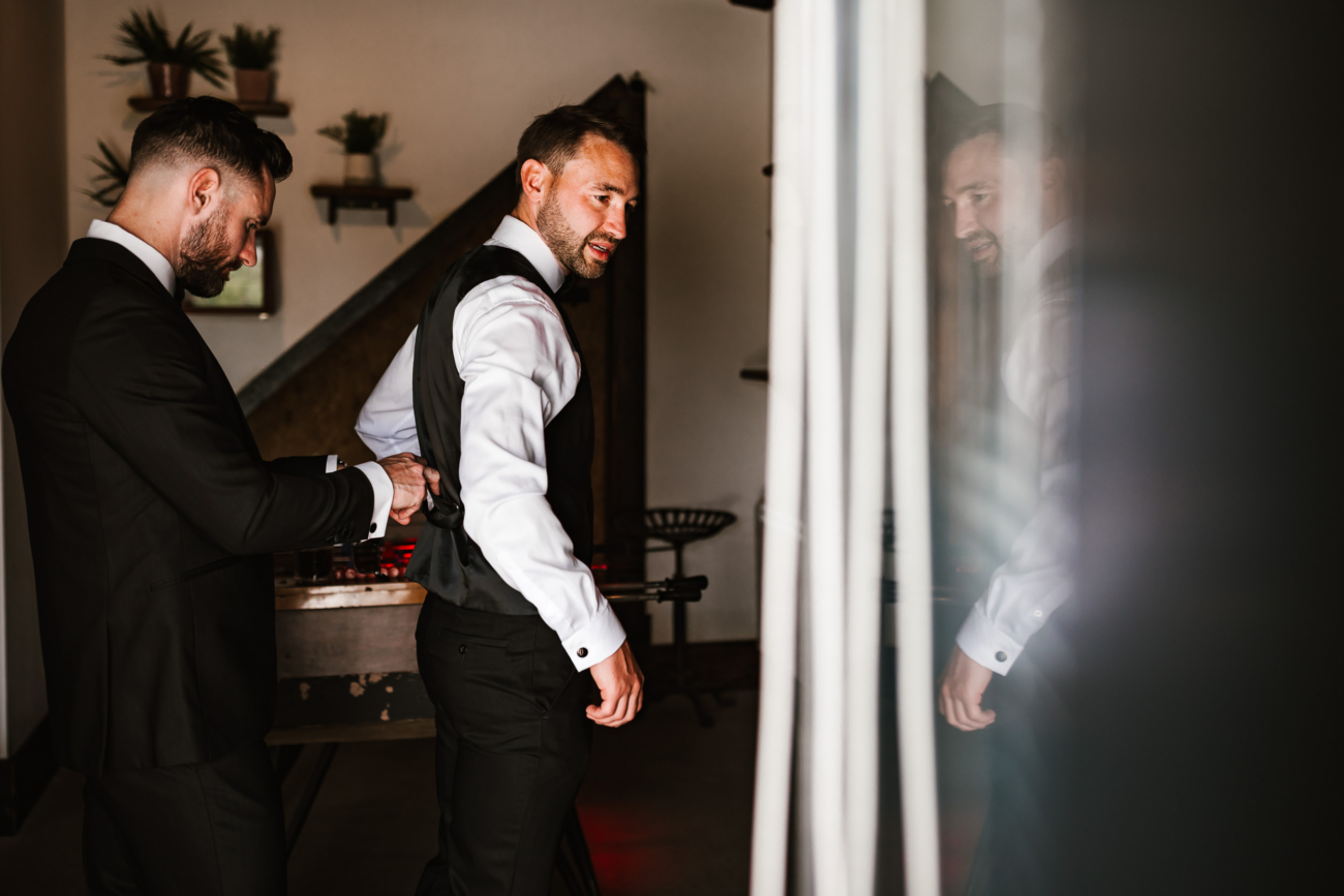 Groom getting help from his best man getting ready