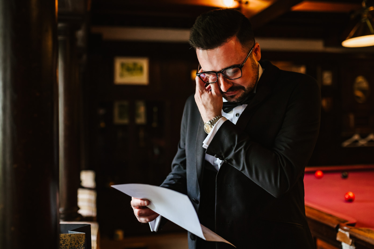 Groom crying reading a letter at eaves Hall