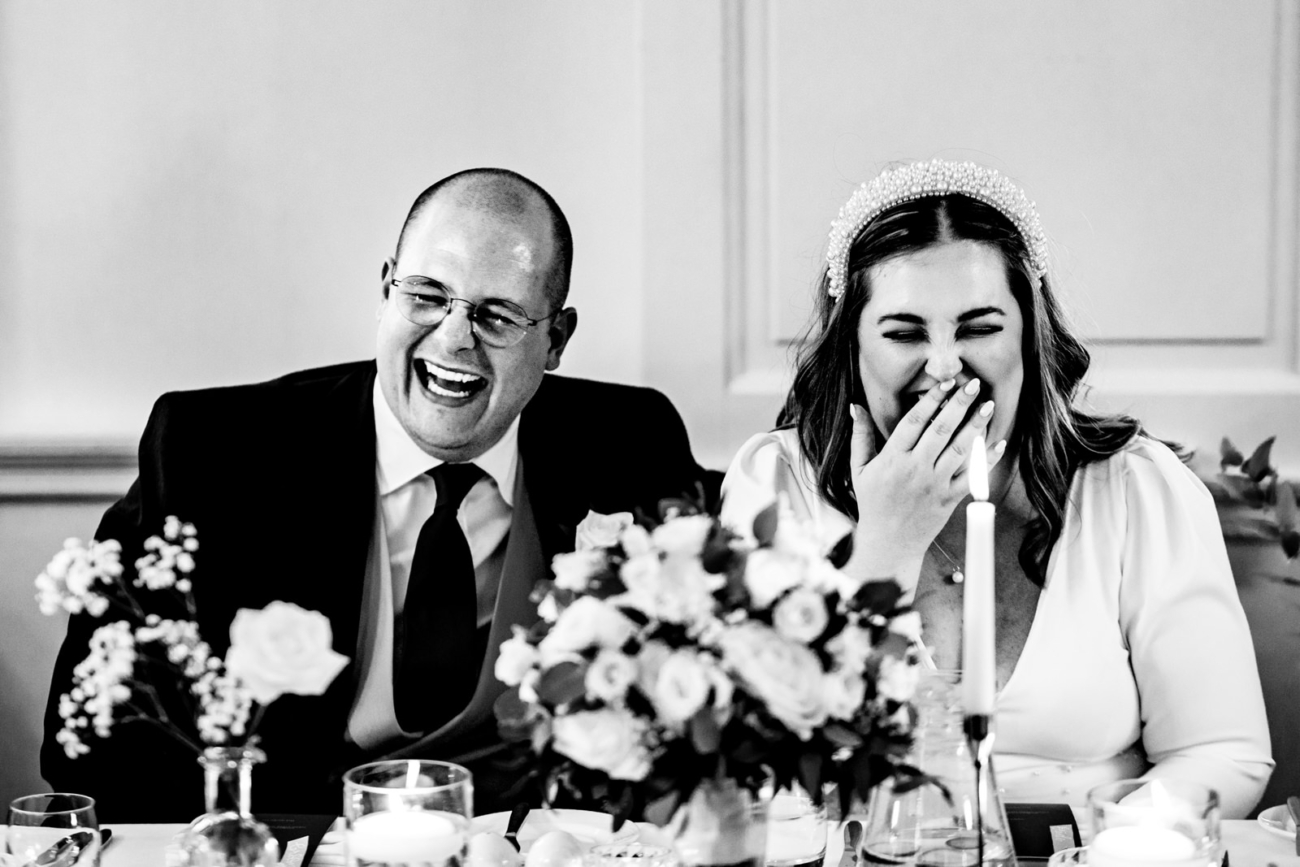 Bride and groom laughing during speeches
