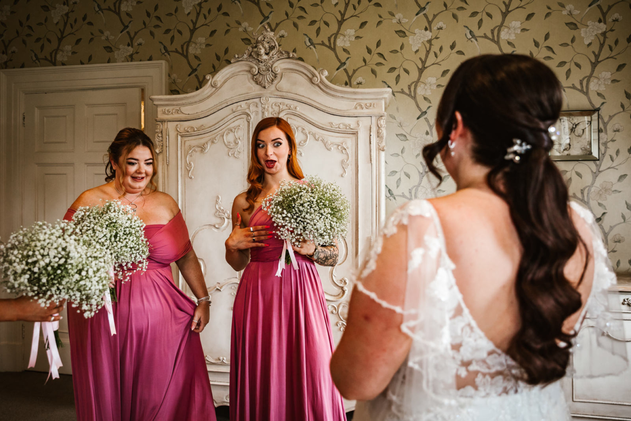 Bridesmaids seeing the bride in her dress