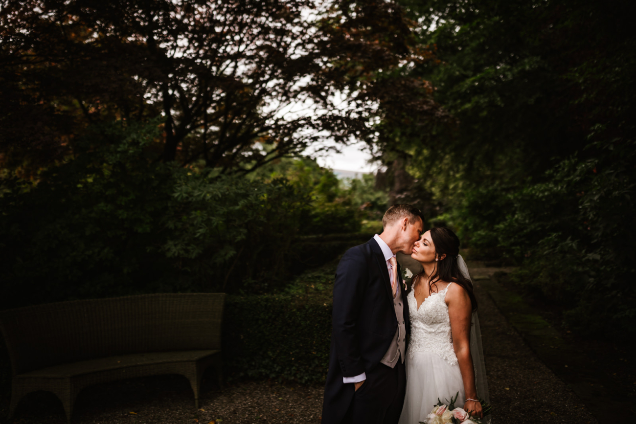 Groom kissing the bride in the gardens at eaves hall